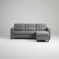 Gray sectional sofa in a living room setting with a white wall and wooden floor.
