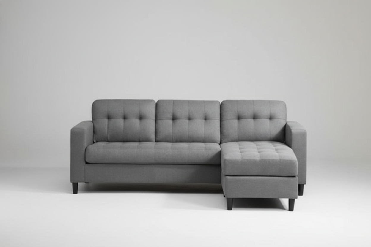 Gray sectional sofa in a living room setting with a white wall and wooden floor.