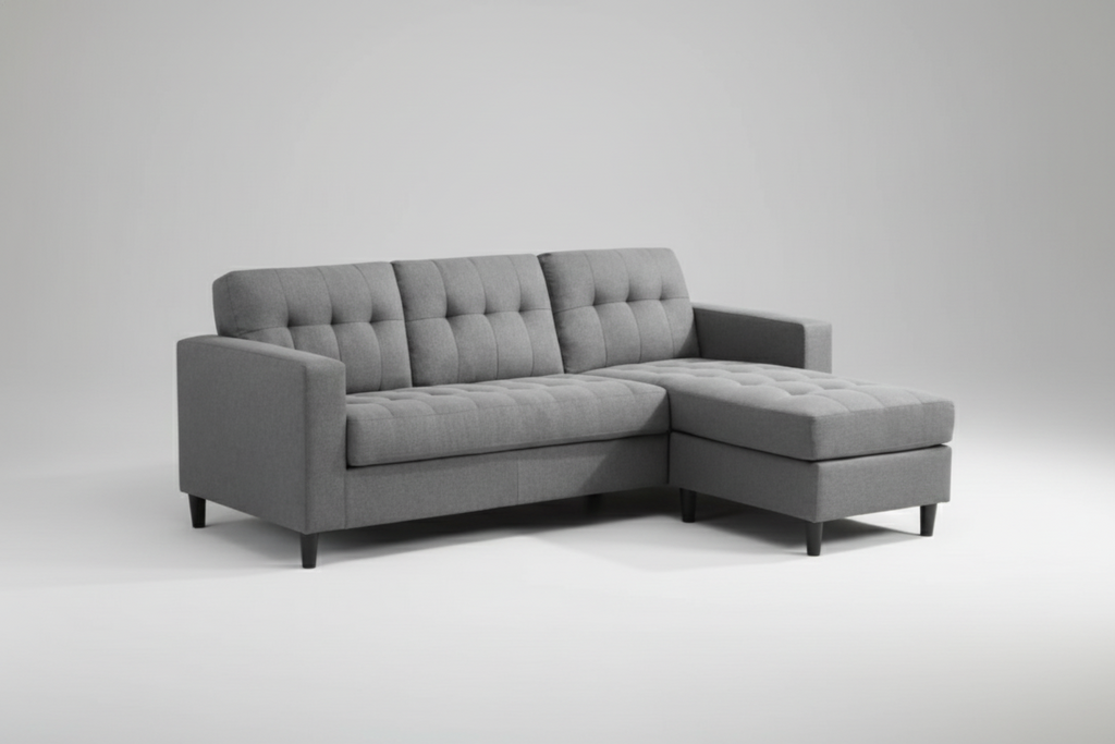 Gray sectional sofa in a living room setting with a white wall and window blinds.