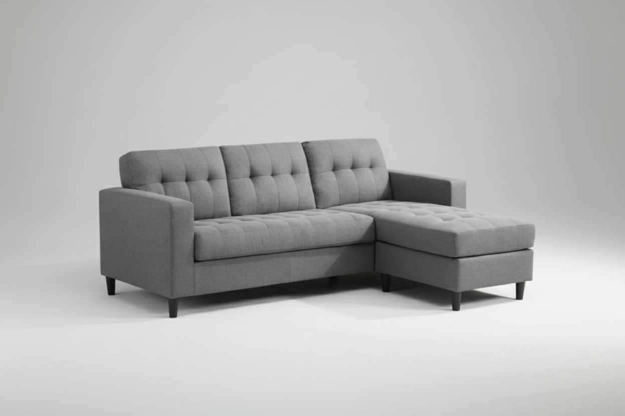 Gray sectional sofa in a living room setting with a white wall and window blinds.