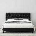 Black tufted bed with white bedding in a bedroom setting