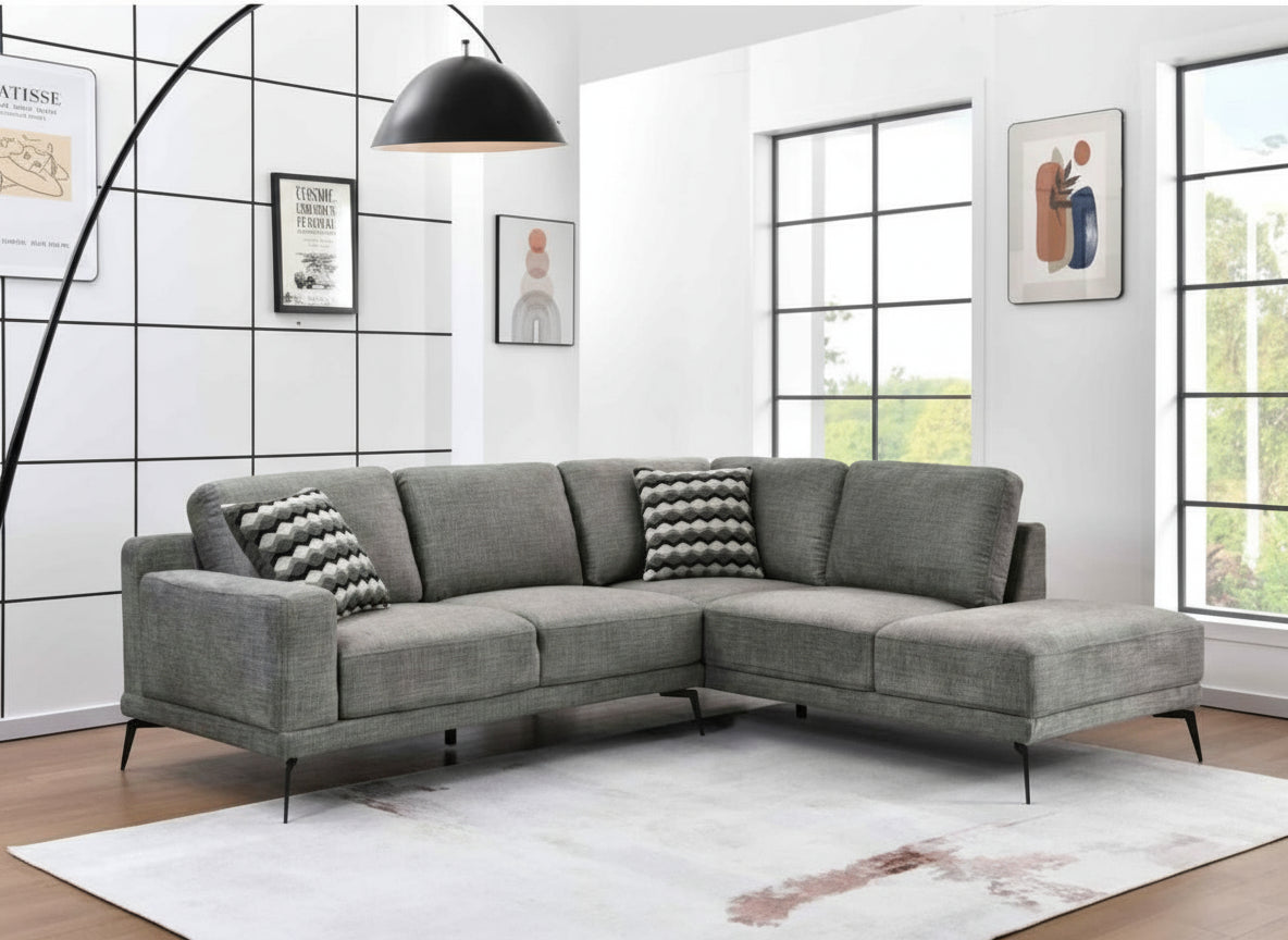 Gray sectional sofa in a room with large windows and modern decor.