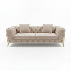 Beige tufted sofa with two pillows on a reflective floor.