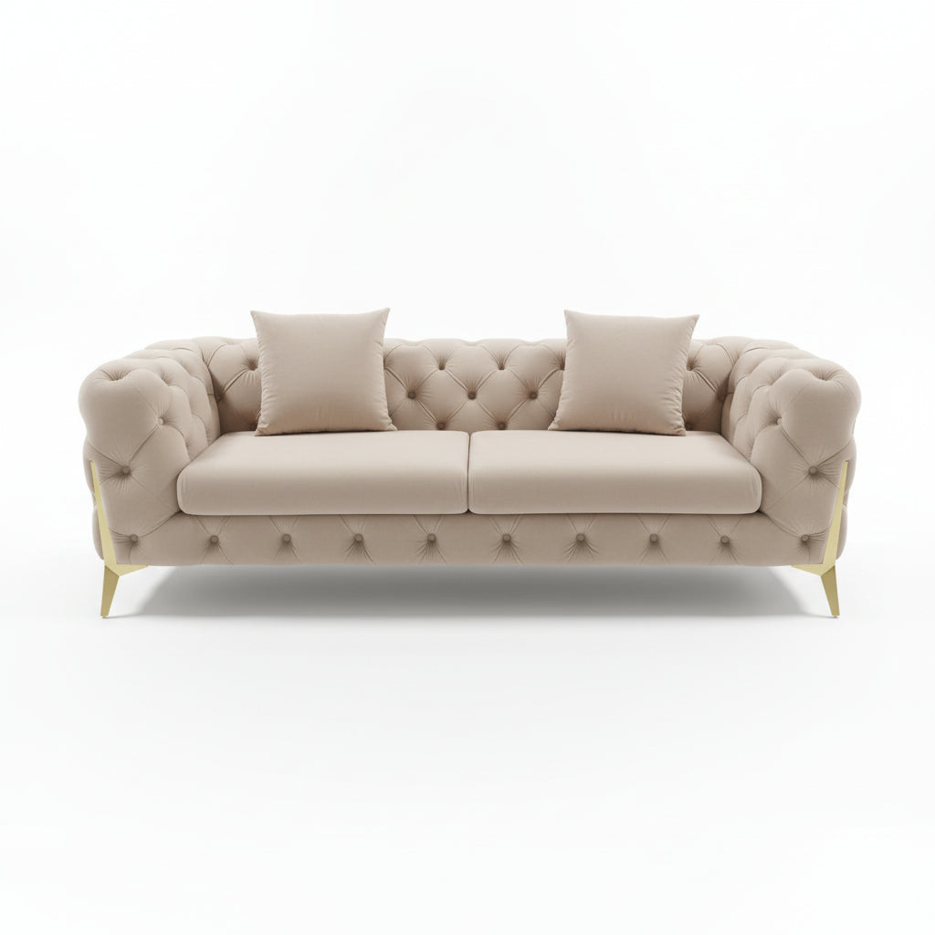 Beige tufted sofa with two pillows on a reflective floor.