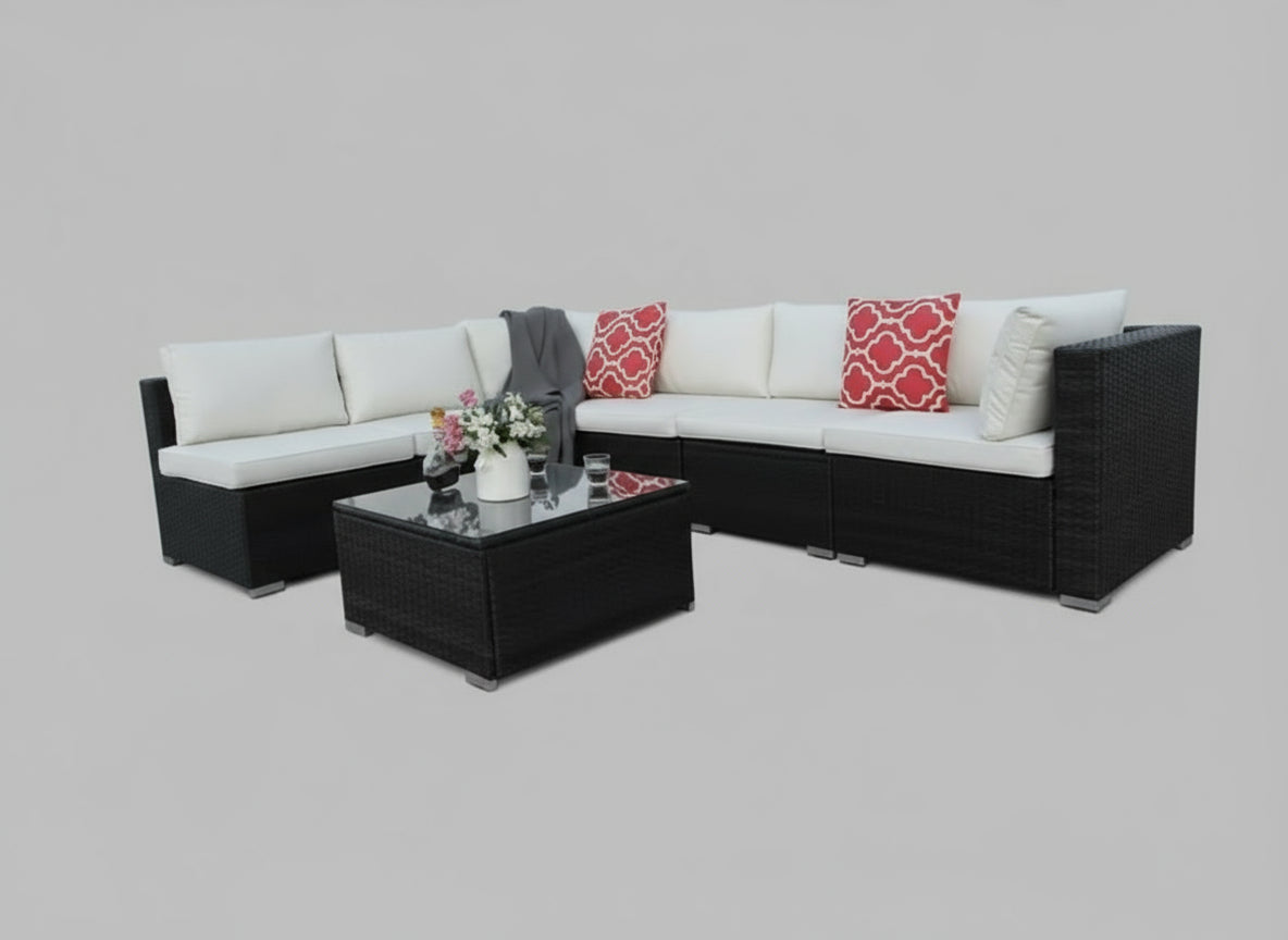 Outdoor patio furniture set with white cushions and red patterned pillows on a patio.