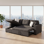 A dark gray modular sectional sofa with a chaise lounge and raised backrest, shown in a bright modern room with large windows overlooking a city skyline. A potted plant stands near the window.