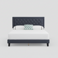 Bed with tufted navy headboard and white bedding on a light gray background